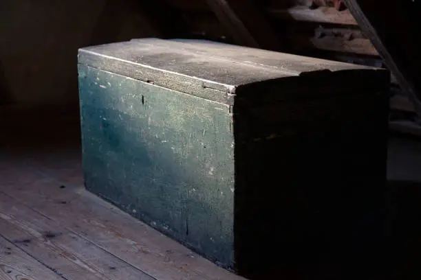 صندوق خشبي قديم مغلق في ضوء خافت يعكس الغموض