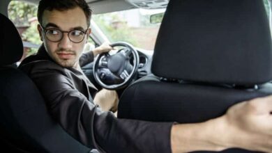 سائق تاكسي يتفحص صندوقًا خلف المقعد بحيرة، في موقف إنساني أخلاقي