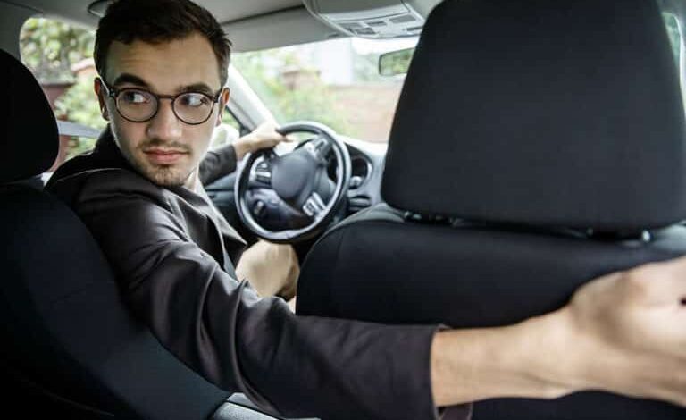 سائق تاكسي يتفحص صندوقًا خلف المقعد بحيرة، في موقف إنساني أخلاقي