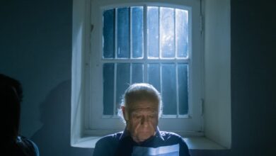 رجل كبير يقرأ رسالة من صندوق خشبي قديم بجانب نافذة مضيئة