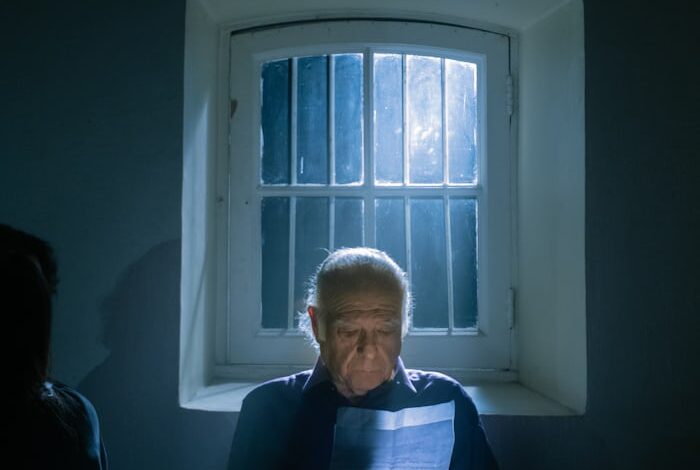 رجل كبير يقرأ رسالة من صندوق خشبي قديم بجانب نافذة مضيئة