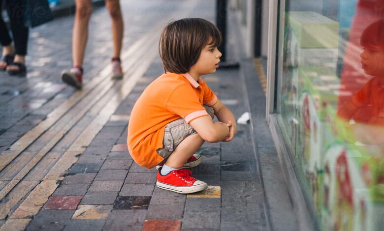 طفل يحدق في واجهة محل أحذية ليلة العيد بعينين مليئتين بالرجاء