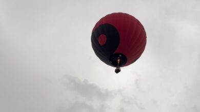 طفل يطير في السماء ممسكًا ببالون أحمر في مغامرة خيالية