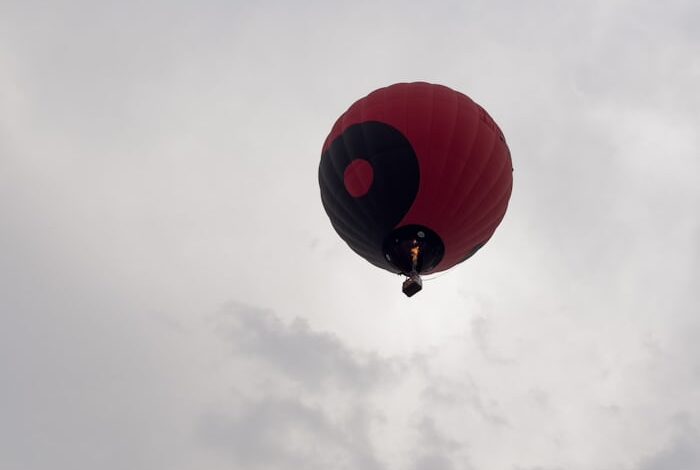 طفل يطير في السماء ممسكًا ببالون أحمر في مغامرة خيالية